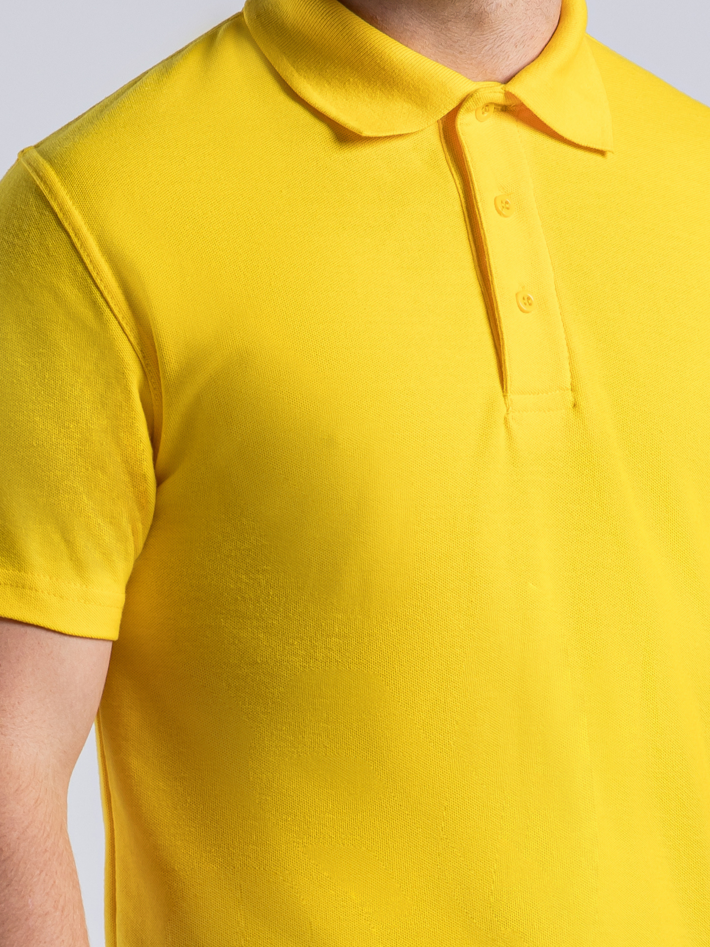 Yellow polo shirt showing three button placket plus spare button 