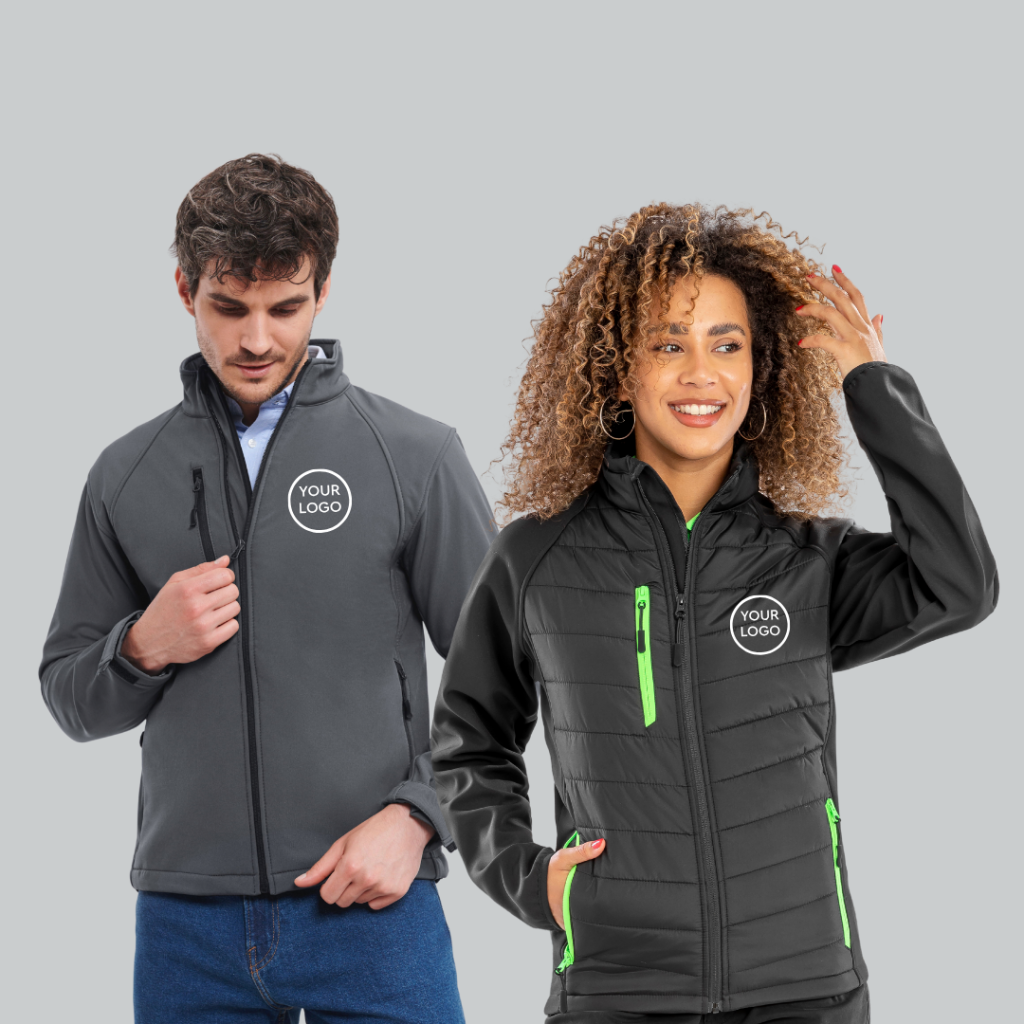 Man on the left is wearing blue jeans and a blue shirt with a grey shoftshell, the woman on the right is wearing a black jacket with neon green zips.